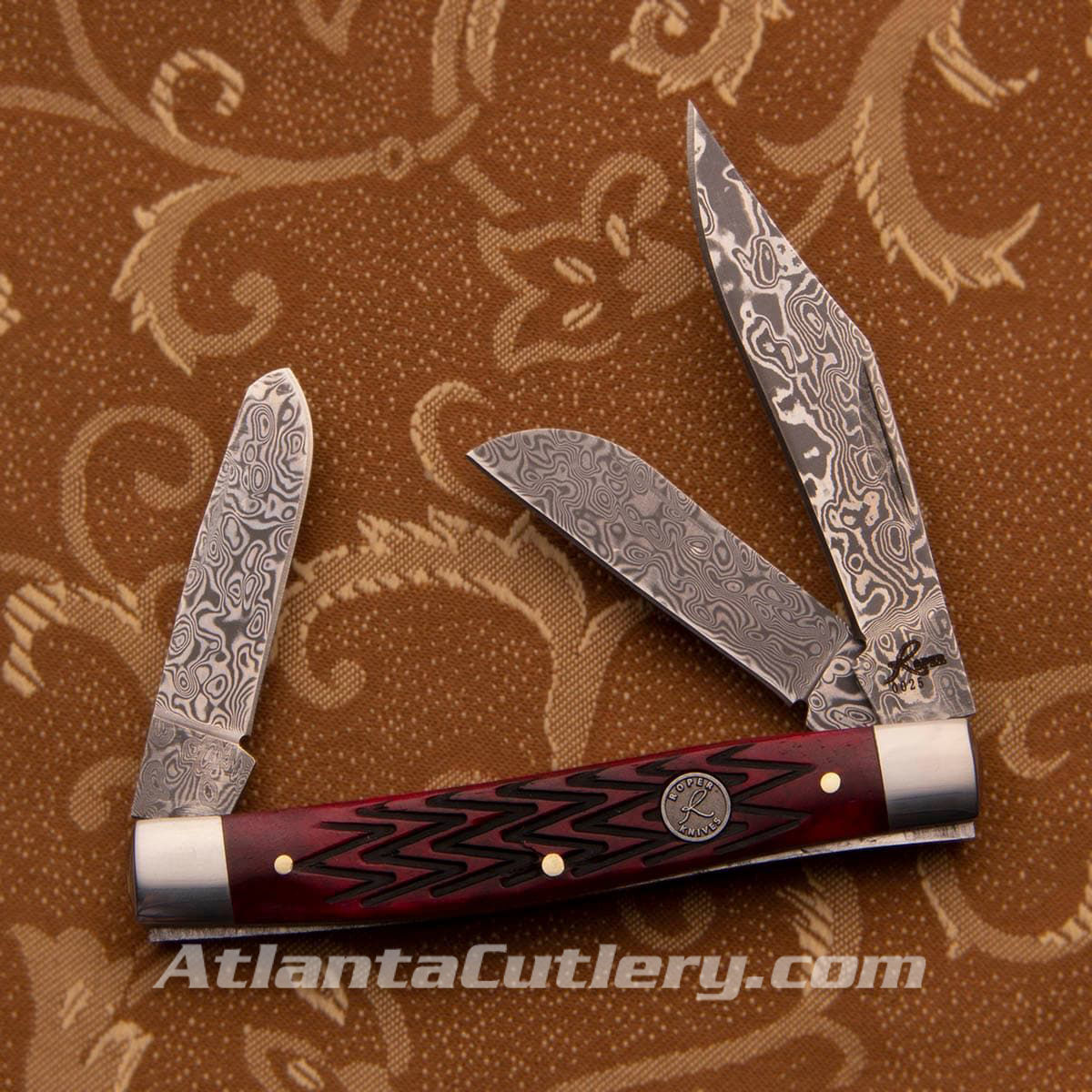 3 blades of this Roper pocket knife are 57 layer Damascus, the red jigged bone handles have a zigzag texture