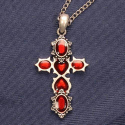 silver necklace with 6 red stones in the shape of a cross, 2 heart-shaped stones in center are facing each other