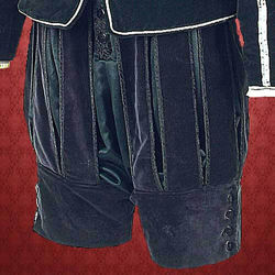 black cotton Renaissance breeches have velvet slash panels trimmed in black brocade, wide velvet cuffs, elastic waist, button front